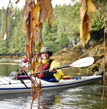 A kayaker paddling through hanging kelp