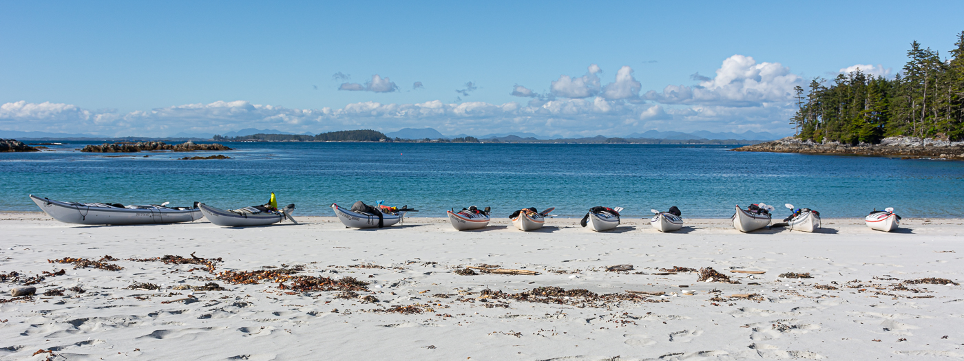 A group of kayaks on a white sand beach in the Great Bear Rainforest