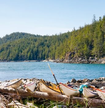 A number of kayaks and paddlers resting on the beach in Desolation Sound