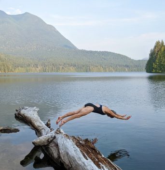A woman jumping in to a freshwater lake in Desolation Sound