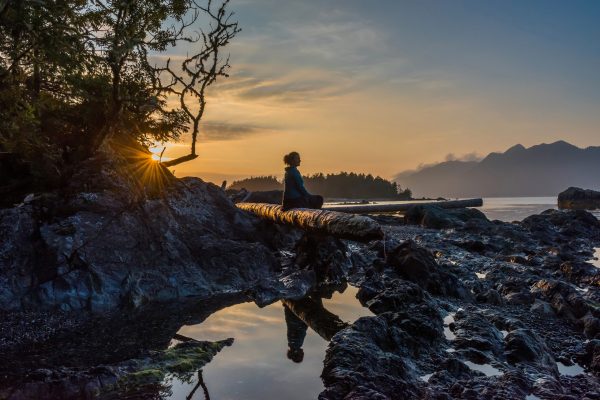 Woman sitting on driftwood on Vancouver Island