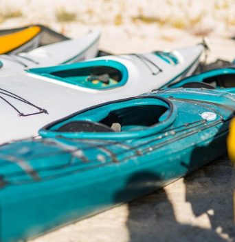 A collection of kayaks resting on a white sand beach