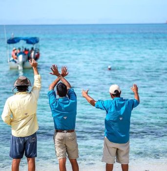Guides waving goodbye to their guest's boat