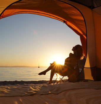A guest lounging in a beach chair outside of a tent in Baja Mexico