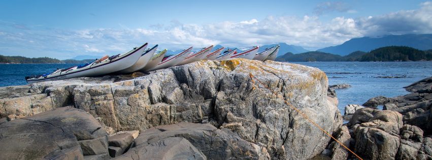 A group of kayaks resting atop a rock in Coastal BC